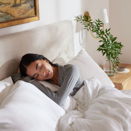 Woman sleeping peacefully on a soft Sillo silk pillowcase in a cozy, neutral bedroom — showcasing the antibacterial and hypoallergenic benefits of antimicrobial silk for better sleep hygiene and clearer skin.