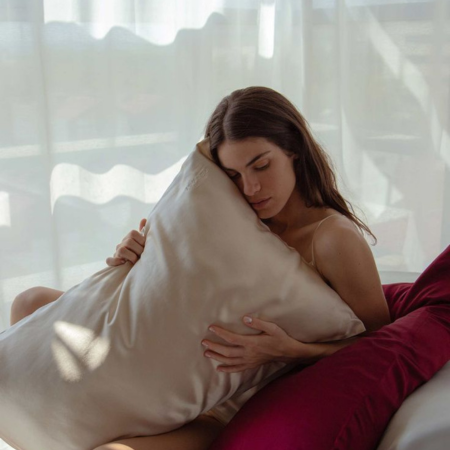 Woman resting on a champagne-colored Sillo silk pillowcase made from 22-Momme mulberry silk, designed to prevent acne, reduce bacteria buildup, and support clearer, hydrated skin.