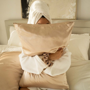 Best hypoallergenic pillowcase for sensitive skin — woman in robe holding champagne Sillo silk pillowcase.