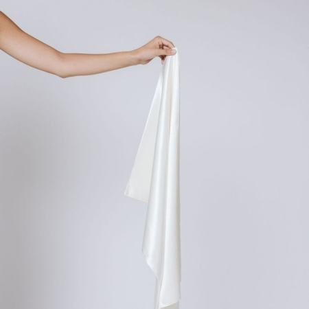 Hand holding a Ivory White silk pillowcase, showing Sillo’s care routine for washing and drying silk to preserve its smooth texture.