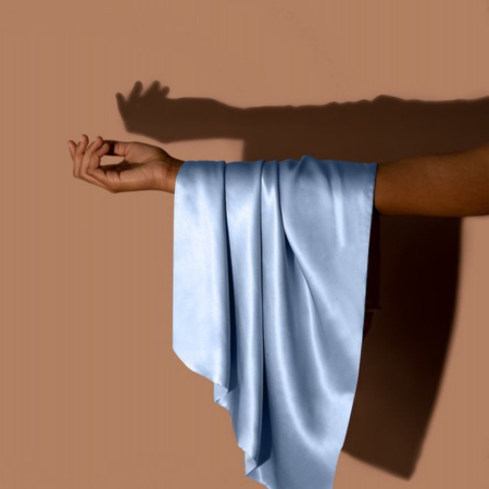 How to wash silk pillowcases — light blue silk fabric draped over arm showing Sillo gentle care approach.