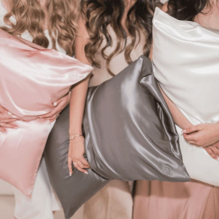 The Momme difference — deciphering Momme counts and thread counts for luxurious sleep.Image shows three women holding blush, charcoal, and ivory Sillo silk pillowcases.