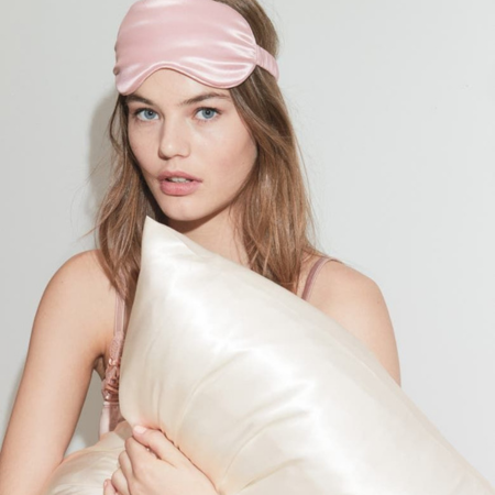 How to choose the best silk pillowcase — woman in pink sleep mask holding ivory Sillo silk pillowcase.