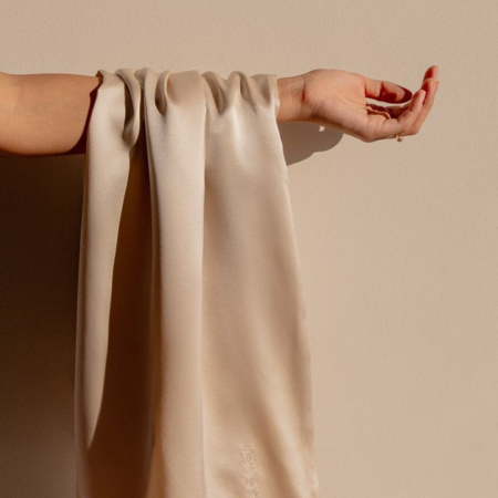 Sillo silk pillowcase in light champagne 22-Momme mulberry silk draped over an arm — highlighting its smooth, hypoallergenic texture that’s gentle on sensitive skin and hair.