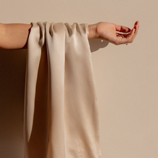 Sillo silk pillowcase in light champagne 22-Momme mulberry silk draped over an arm — highlighting its smooth, hypoallergenic texture that’s gentle on sensitive skin and hair.