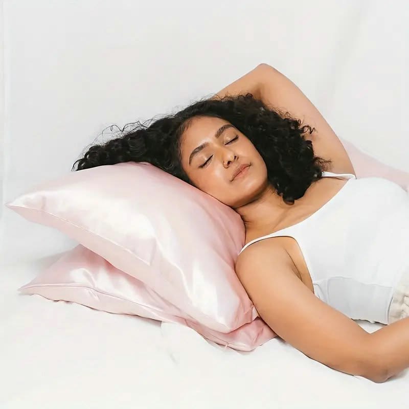 A women with curly frizzy hair sleeping on Sillo blush pink mulberry silk pillowcase