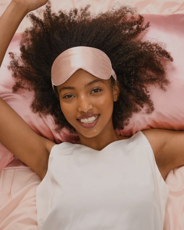 A women with curly hair sleeping on Sillo blush pink silk pillowcase for curly hair helps prevent breakage frizz 