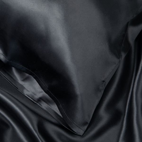 Close-up of Black Sillo silk pillowcase — 22 Momme 6A grade organic Mulberry silk woven with silver ions for antibacterial protection, showing smooth texture, envelope-style closure, and natural sheen; gentle on skin and hair.