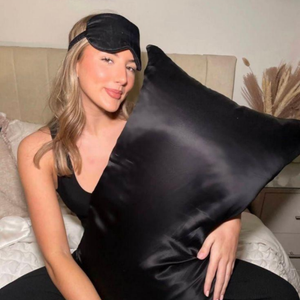 Lifestyle image of woman sleeping on Black Sillo silk pillowcase — smooth, temperature-regulating silk that helps prevent acne, wrinkles, frizz, breakage  while caring for sensitive skin.