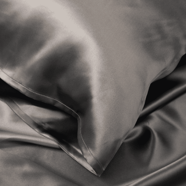 Close-up of Charcoal Grey Sillo silk pillowcase — 22 Momme 6A grade organic Mulberry silk woven with silver ions for antibacterial protection, showing smooth texture, envelope-style closure, and natural sheen; gentle on skin and hair.
