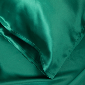 Close-up of Emerald Green Sillo silk pillowcase — 22-Momme 6A grade organic Mulberry silk woven with silver ions for antibacterial protection, showing smooth texture, envelope-style closure, and natural sheen; gentle on skin and hair.