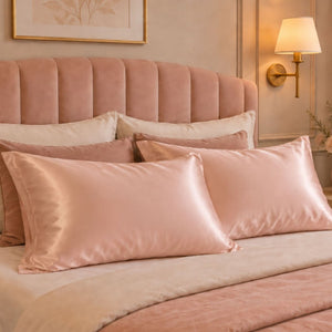 A styled bedroom scene showing a bed with two blush pink Sillo silk pillowcases woven with silver ions 22 momme mulberry, with envelope closure.