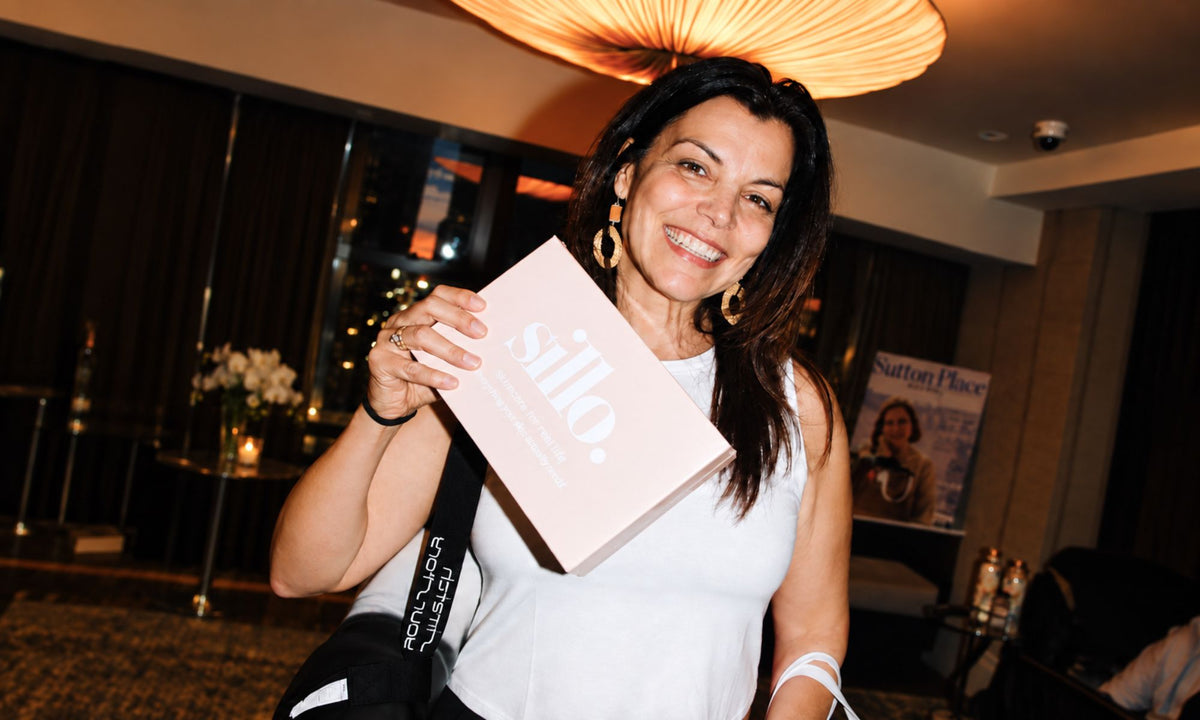 Real Sillo customer smiling as she holds a Sillo silk pillowcase gift set, which includes two silk pillowcases and care wash bag. 