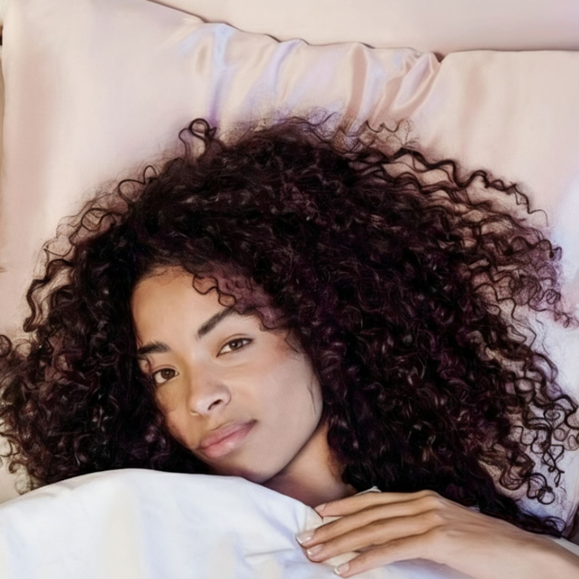 Woman resting on the Sillo silk pillowcase a hypoallergenic, silver-ion infused 22-Momme mulberry silk pillowcase that resists odor, reduces bacteria buildup, and keeps sensitive skin clear and irritation-free.