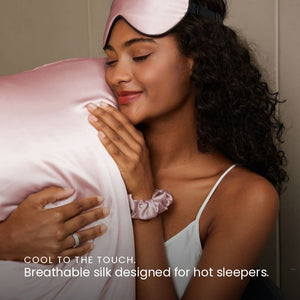 Lifestyle photo of woman holding Blush Pink Sillo silk pillowcase — soft 22-Momme organic Mulberry silk woven with silver ions for acne-prone, sensitive skin and hair; helps reduce wrinkles and signs of aging. Cooling, hypoallergenic, and gentle for daily use.