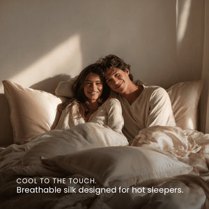 Light Champagne Sillo silk pillowcase styled on bed in modern bedroom; 22 Momme Mulberry silk woven with silver ions for acne-prone, sensitive skin and hot sleepers seeking cool, temperature-regulating, wrinkle-reducing sleep.