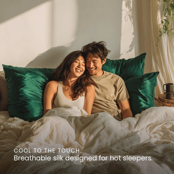 Emerald Green Sillo silk pillowcase styled on bed in modern bedroom; 22-Momme Mulberry silk woven with silver ions for acne-prone, sensitive skin and hot sleepers seeking cool, temperature-regulating, wrinkle-reducing sleep.