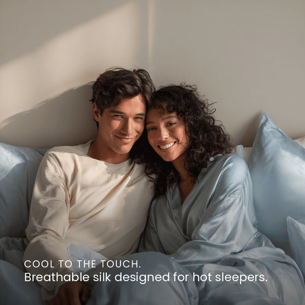 Haze Blue Sillo silk pillowcase styled on bed in modern bedroom; 22 Momme Mulberry silk woven with silver ions for acne-prone, sensitive skin and hot sleepers seeking cool, temperature-regulating, wrinkle-reducing sleep.