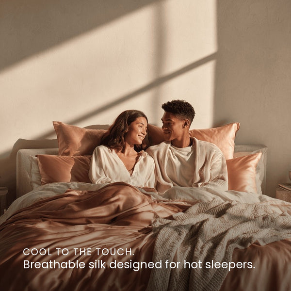 Rose Pink Sillo silk pillowcase styled on bed in modern bedroom; 22 Momme Mulberry silk woven with silver ions for acne-prone, sensitive skin and hot sleepers seeking cool, temperature-regulating, wrinkle-reducing sleep.