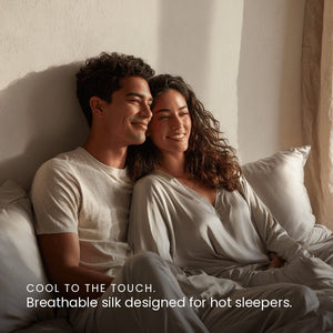 Silver Sillo silk pillowcase styled on bed in modern bedroom; 22 Momme Mulberry silk woven with silver ions for acne-prone, sensitive skin and hot sleepers seeking cool, temperature-regulating, wrinkle-reducing sleep.