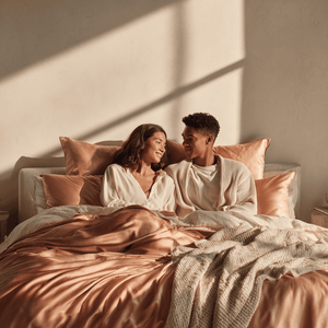 Rose Pink Sillo silk pillowcase styled on bed in modern bedroom; 22 Momme Mulberry silk woven with silver ions for acne-prone, sensitive skin and hot sleepers seeking cool, temperature-regulating, wrinkle-reducing sleep.