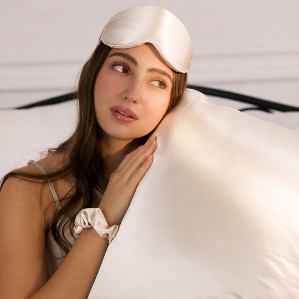 women with healthy radiant hair relaxing on a bed with Ivory White Sillo 22 Momme organic mulberry silk pillowcases, highlighting frizz reduction, anti acne benefits, hypoallergenic comfort, and gentle skin friendly sleep support.